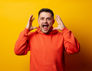 Handsome man in hoodie on yellow background