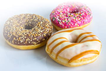 Three doughnuts with colored icing and topping