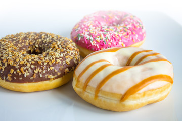 Three doughnuts with colored icing and topping