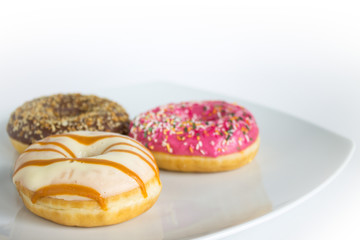 Three doughnuts with colored icing and topping