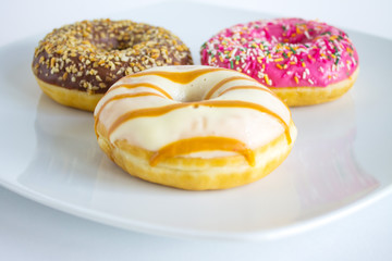Three doughnuts with colored icing and topping