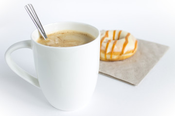 A large white cappuccino Cup and a frosting doughnut