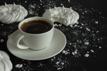 Cup of coffee and meringue on black background