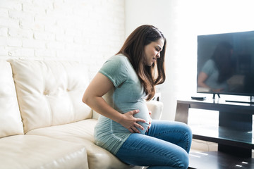 Pregnant Female Grimacing With Hands On Baby Bump