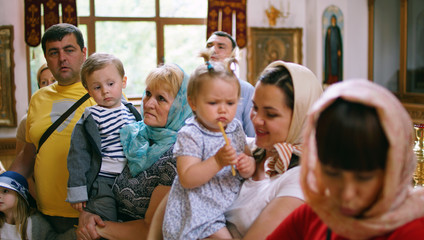 Little girls with others person in Orthodox Church, first visit to a Church