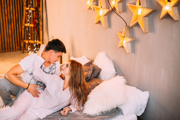 guy and girl in pajamas are lying on the bed and kissing. stylis