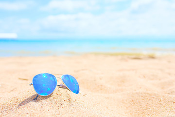 Fototapeta na wymiar Sunglasses on the beach with ocean and sky on background
