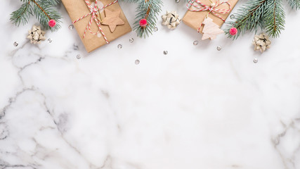 Christmas or New Year banner. Xmas greeting card. Christmas gifts and fir tree branches on white marble background. Flat lay, top view, overhead