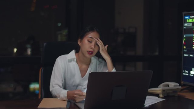Millennial young Chinese businesswoman work late night stress out with project research problem on laptop in meeting room at small modern office. Asia people occupational burnout syndrome. Slow motion
