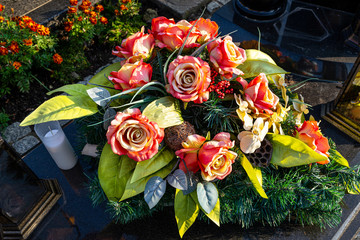 Artificial flowers and candles lie on the tombstone in the cemetery.