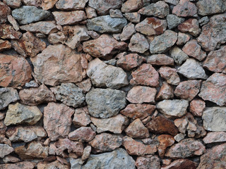 Wall of multi-colored large stones. Stone Wall Pattern.