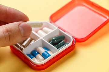 Dose pill box with medical pills on yellow background. Top view. Flat lay. Copy space. Pharmaceutical medicine pills, tablets and capsules. Medicine concepts. Trendy pastel color