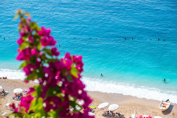 Fototapeta na wymiar Turquoise tropical beach appearing behind bougainvillea flowers. Kaputas Beach , located in Antalya , Turkey