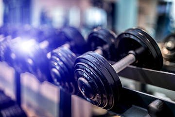 Fototapeta na wymiar Rows of dumbbells in the gym with blurred background. Closeup. Sport equipment. Healthy life concept.