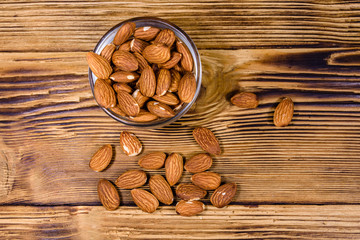 Glass bowl with the peeled almond nuts on wooden table. Top view