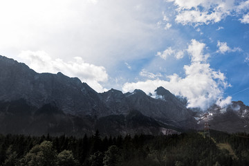 Fototapeta premium Alps mountains, summer panoramic landscape. Blue sky and cable car tower above the forest