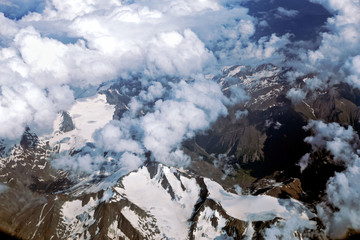 Alps and clouds from the plane. Earth through the porthole. Aerial view, concept of flight trip