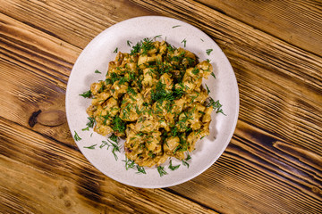 Plate with champignons stewed in sour cream on a wooden table. Top view