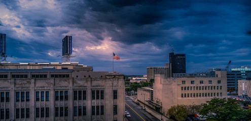 American flag captured brightly on top of a city scape before a storm