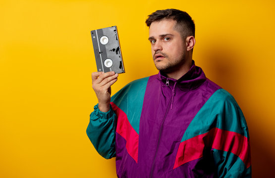Style man in 90s tracksuit with VHS cassette on yellow background