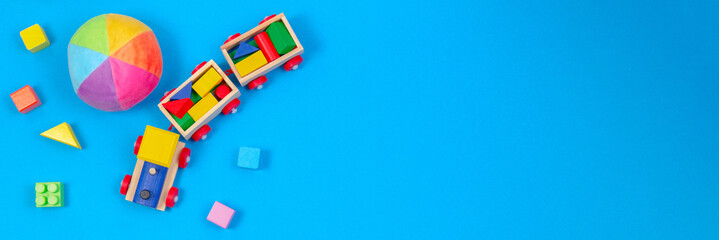 Baby kinderen speelgoed banner achtergrond. Houten trein, zachte bal en kleurrijke blokken op blauwe achtergrond
