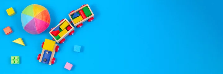 Foto auf Acrylglas Tagesbetreuung Baby Kinder Spielzeug Banner Hintergrund. Holzzug, weicher Ball und bunte Blöcke auf blauem Hintergrund