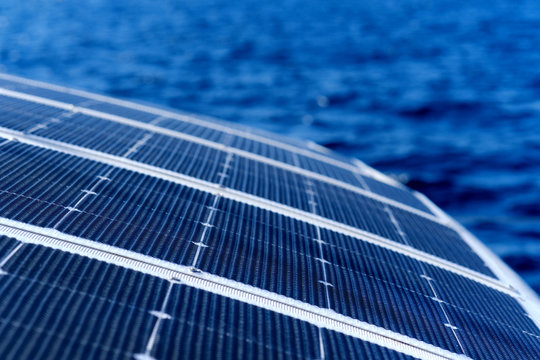 Close up view part of solar panel on dock of sailboat and blue sea waters during sunny day outdoors
