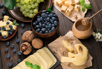 .blueberry grapes and cheese on a wooden background