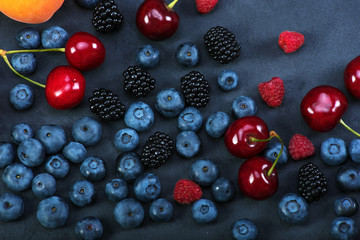 Blackberries,blueberries,raspberries,cherries on black concrete background. Healthy food