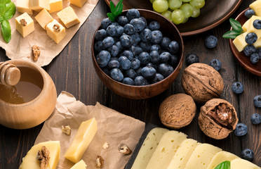 .blueberry grapes and cheese on a wooden background