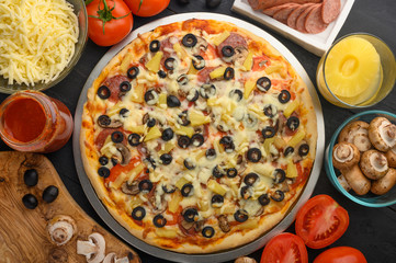 Pizza on a black background with ingredients, tomatoes, salami, mushrooms, sauce and mazzarella cheese. Italian pizza, culinary recipes concept, menu, restaurant, gourmet cuisine