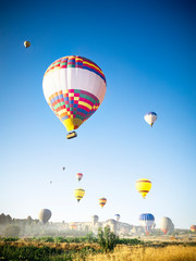 Big colorful balloons taking off on a foggy morning over beautiful landscape of Cappadocia, Turkey.