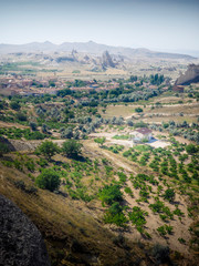 Fototapeta na wymiar Beautiful view from the top of the mountain to the rural landscape of Turkey, Cappadocia with single farm houses scattered across the plain.