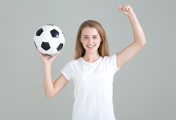 Football fan. Young woman with a soccer ball raised her hand up in a sign of winning.