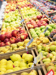 A variety of colorful fruits are on display in the supermarket. Pears, apples.