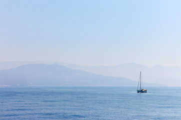 Fototapeta premium yacht on the background of the coast and mountains from the sea in the morning fog