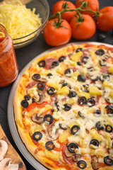 Italian pizza with ingredients on a dark background. Vertical photo.