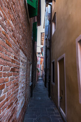 Narrow passage between ancient buildings in city center. Caorle Italy