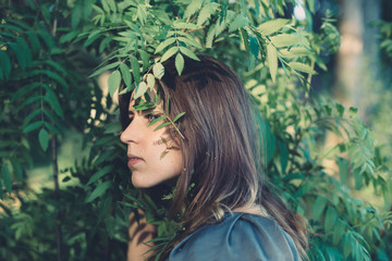Portrait of a young girl with leaves and herbarium outdoors next to a tree