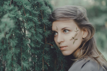 Portrait of a young girl with leaves and herbarium outdoors next to a tree