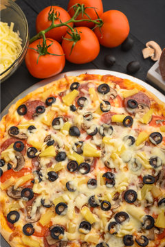 Italian pizza with ingredients on a dark background. Vertical photo.