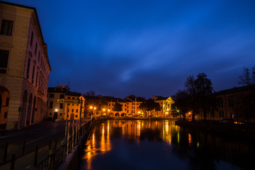 Fototapeta na wymiar Picturesque view on the Sile river from the university bridge Ponte dell'Universita with lights reflections on the water at night Treviso Italy