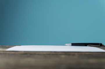 Contract or document with a pen lying on textured wooden desk