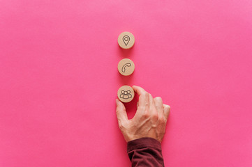 Placing three wooden cut circles wit contact and information icons on them over pink background