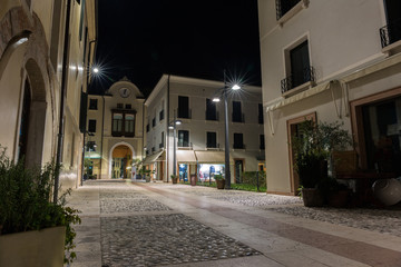Sidewalk in the latin square Piazza del quartiere latino in front of the University at night Treviso Italy