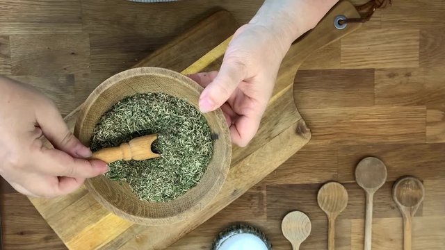 woman mixes dried seasonings and spices in a wooden bowl, the concept of homemade and vegan food