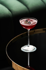 Classic cocktail glass on glass table in night club restaurant, close-up