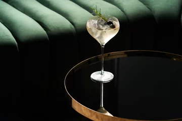 Foto op Plexiglas Classic cocktail glass on glass table in night club restaurant, close-up © Gecko Studio