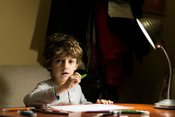Child drawing illuminated by the light of a lamp.