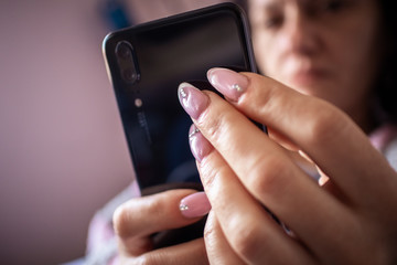 Women's hands with manicured nails holds smartphone